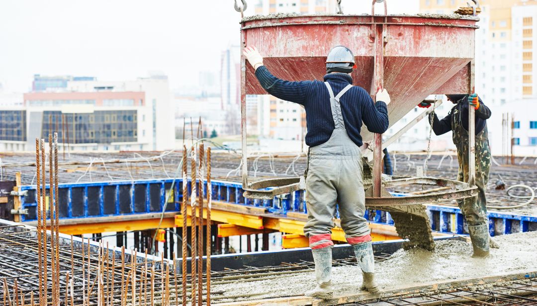 Trabajadores vertiendo concreto premezclado en cimientos de proyecto de construcción